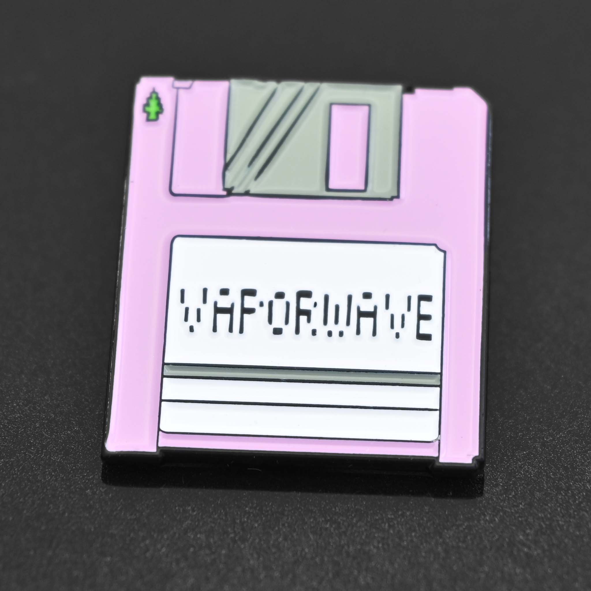 Enamel pin of a pink disk with a label of Vaporwave. 