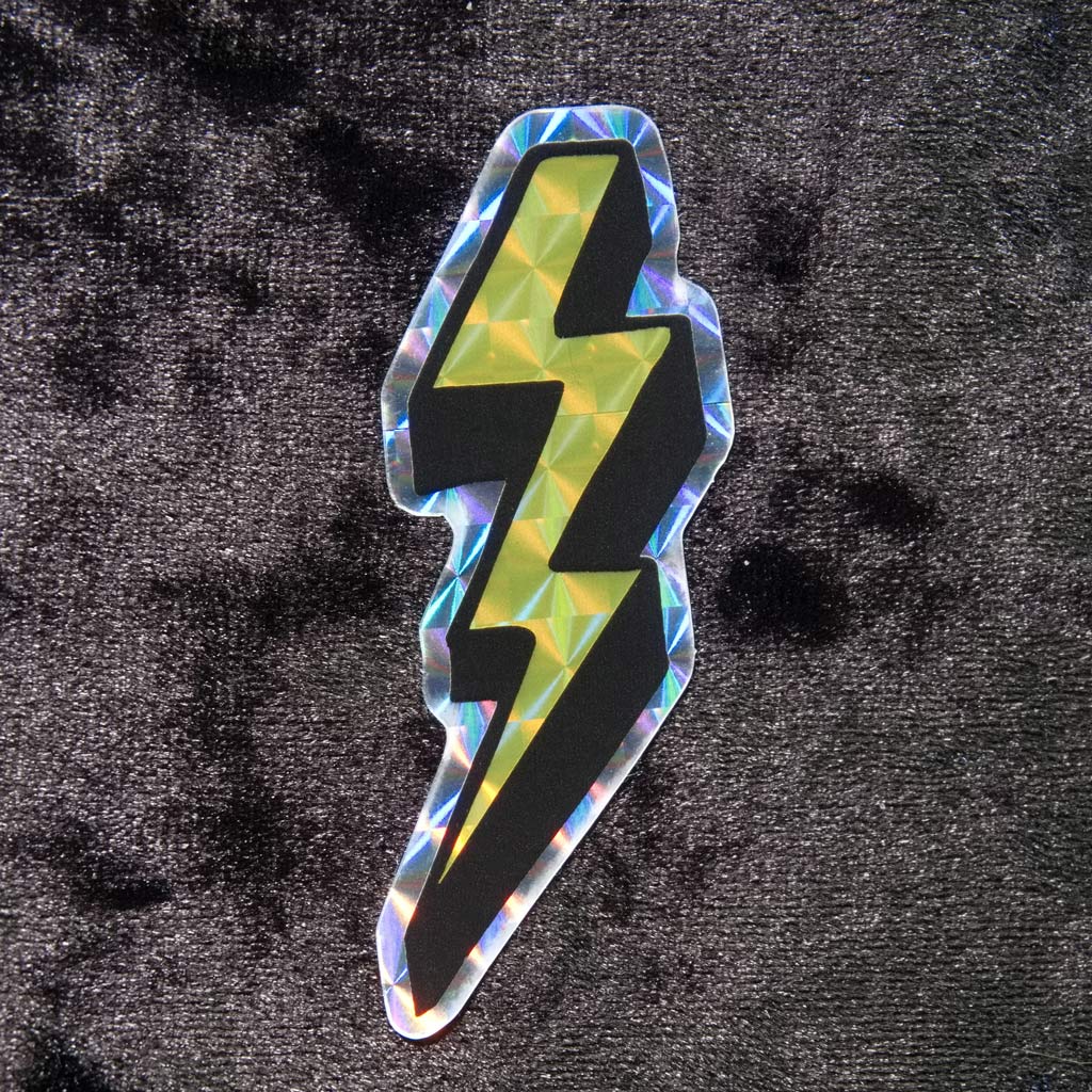 Prismatic or holographic yellow sticker in neon colors and in the shape of the lightning bolts we used to draw in our schoolbooks back in the 80s and 90s